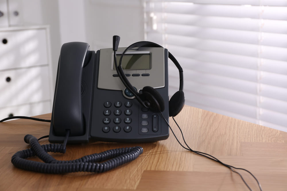 Stationary phone and headset on wooden table indoors