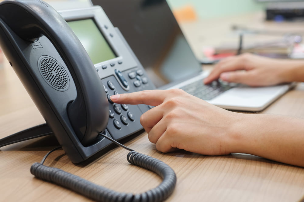 woman hand pointing to dial on an office phone in an office setting