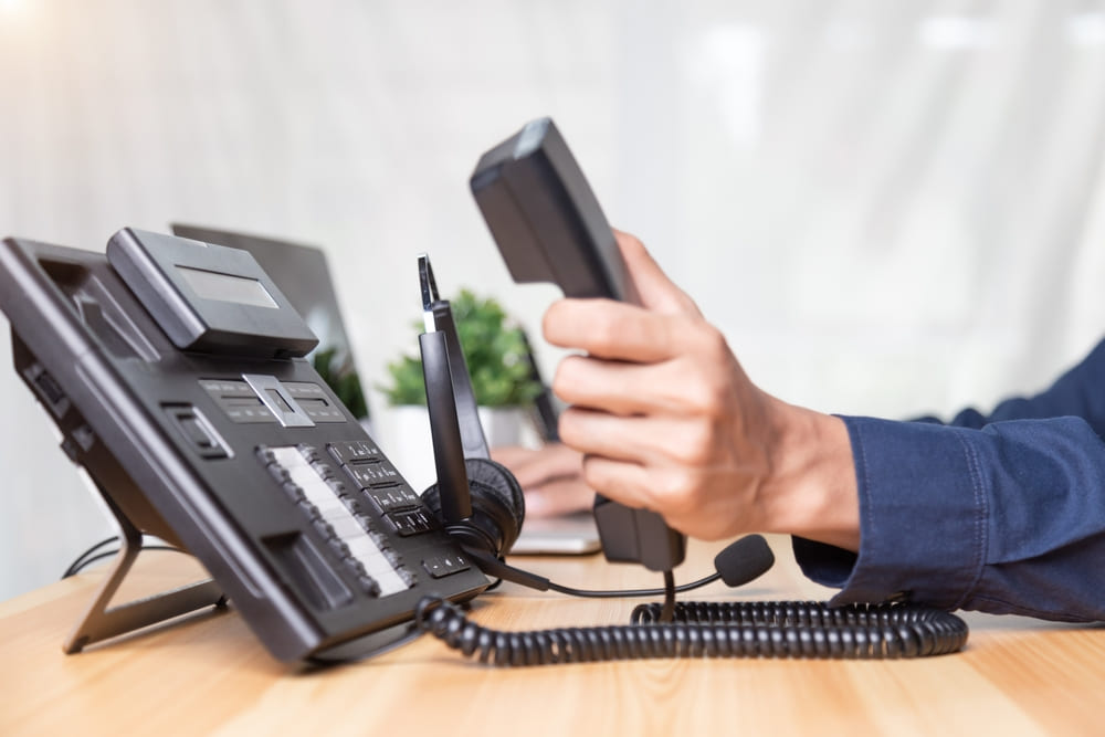 Call center staff man hand point to press the button number on the phone office desk