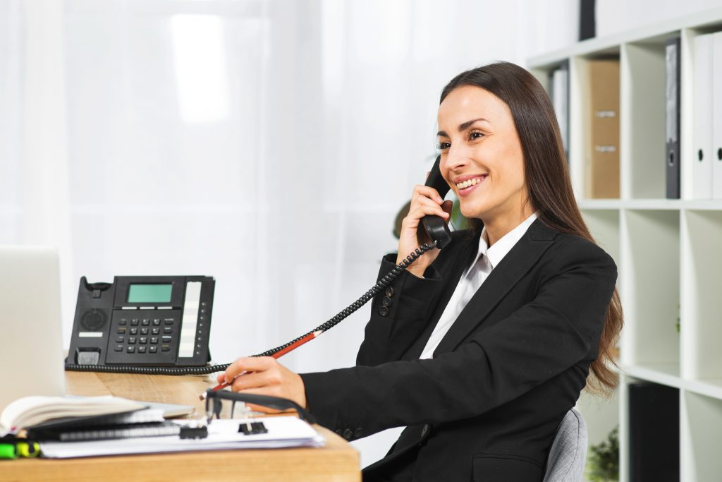 young woman talking on the office phone and smiling